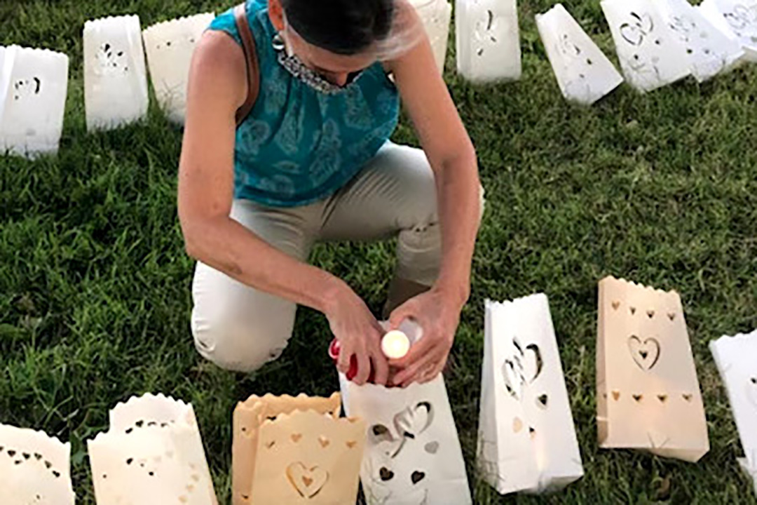 A masked person outside lighting tea lights and placing them in paper bags