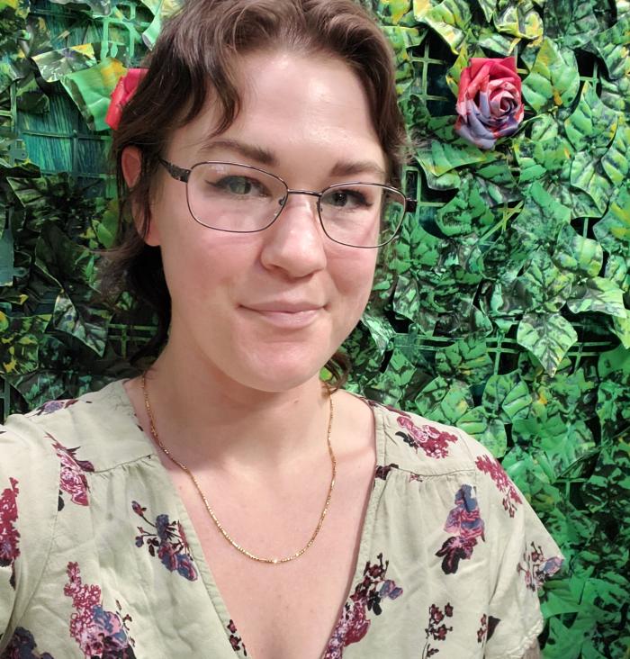 Nicole is White with brown hair. They stand against a floral background.