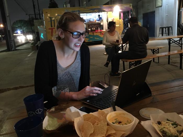 Victoria Karker is a White woman sitting at a table working on a computer. She has light hair and glasses.