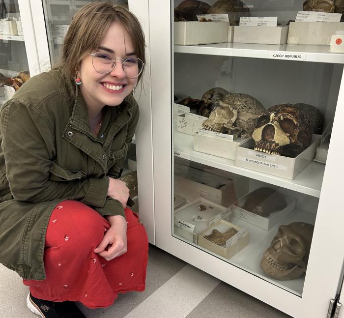 Elissa Hurley kneels beside a case of hominid casts